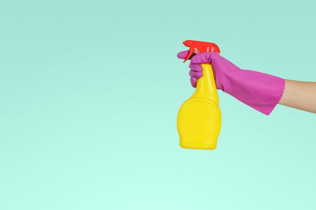 Gloved hand holding a cleaning spray bottle
